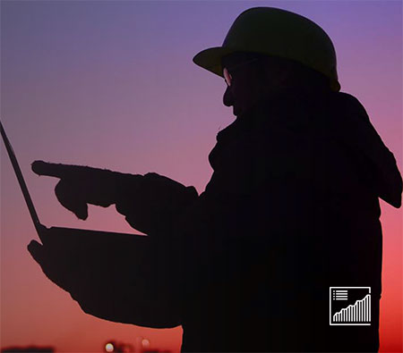 Side view of frontline worker silhouetted against sunset with tablet.
